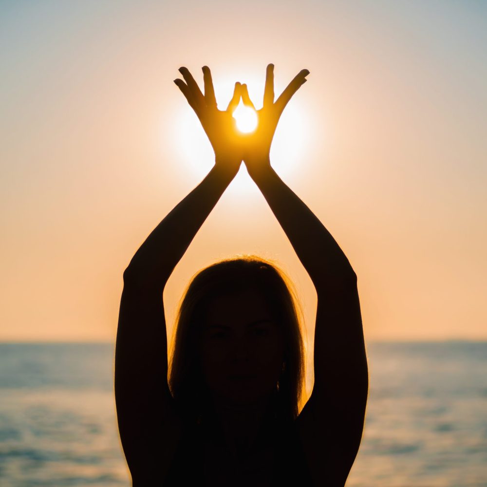 Woman's hands symbolizing prayer and gratitude. Mudra. Yoga concept. Silhouette of female hands on sun background. Beautiful scene